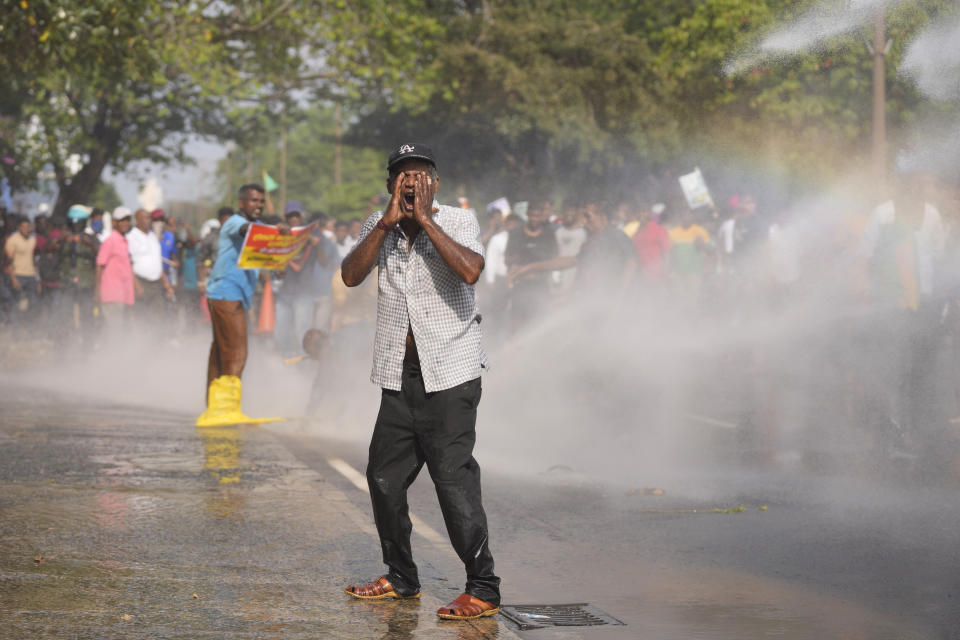 A supporter of Sri Lanka's main opposition covers his face as police fire water cannons to disperse them during a protest rally against high taxes and increases in electricity and fuel charges, in Colombo, Sri Lanka, Tuesday, Jan. 30, 2024. (AP Photo/Eranga Jayawardena)