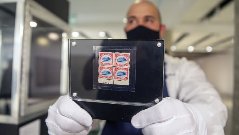 Sotheby’s art handler Dustin Marino holds up a block of four Inverted Jenny stamps showing an upside-down biplane in New York on Thursday, March 11, 2021. A single stamp of the group recently sold for $2 million.