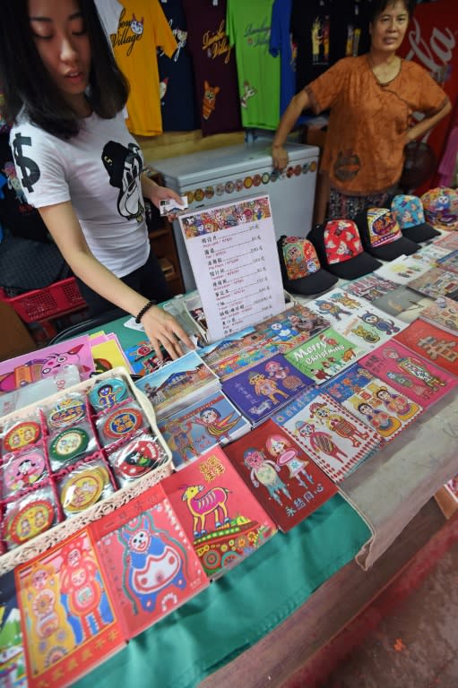 Volunteers help to sell post-cards with the artwork of 93-year-old artist Huang Yung-fu, in the Rainbow Village in Taichung, central Taiwan