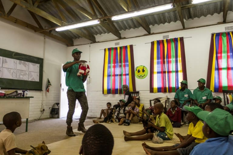 Children sit in class with their puppies to listen to a volunteer tutor in a programme that not only trains dogs but helps their young owners to engage constructively with problems at home or in the community