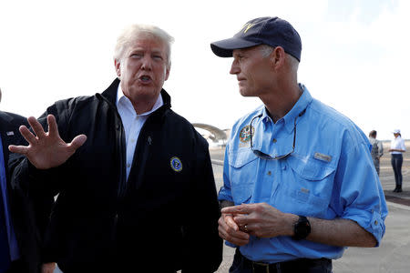 FILE PHOTO: U.S. President Donald Trump talks to Florida Governor Rick Scott (R) as the president arrives to tour storm damage from Hurricane Michael at Eglin Air Force Base, Florida, U.S., October 15, 2018. REUTERS/Kevin Lamarque/File Photo