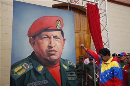 Then Venezuelan Vice President Nicolas Maduro (R) raises his fist next to a painting of then President Hugo Chavez during the commemoration of the 21st anniversary of Chavez's attempted coup d'etat in Caracas in this February 4, 2013 file photo. REUTERS/Jorge Silva