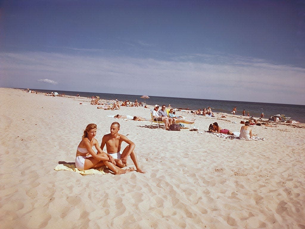 A couple sits on a beach blanket near Katama Shores Inn in Martha's Vineyard, circa 1960