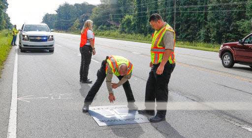 Lexington County Coroners Grey Gain, center and Chandler Clardy paint a cross on South Carolina 378 Thursday, Sept. 14, 2017, where a pedestrian was killed as coroner Margaret Fisher keeps an eye on traffic in this file photo. Federal regulators on Wednesday proposed requiring new vehicles to include automatic emergency braking systems that can avoid lower level crashes as a way to cut down on the high numbers of fatalities on U.S. roads.