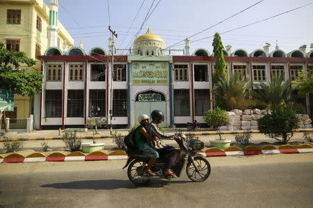 People ride a motorcycle past a mosque, which was burnt in 2013 during anti-Muslim violence and unrest, in Meiktila May 14, 2015. REUTERS/Soe Zeya Tun