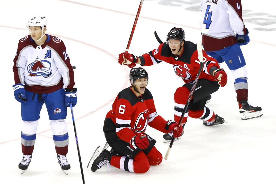 Colorado Avalanche center Nathan MacKinnon (29) looks away as New Jersey Devils defenseman John Marino (6) reacts with left wing Ondrej Palat (18) after scoring a goal during the third period of an NHL hockey game, Tuesday, Feb. 6, 2024, in Newark, N.J. The New Jersey Devils won 5-3. (AP Photo/Noah K. Murray)