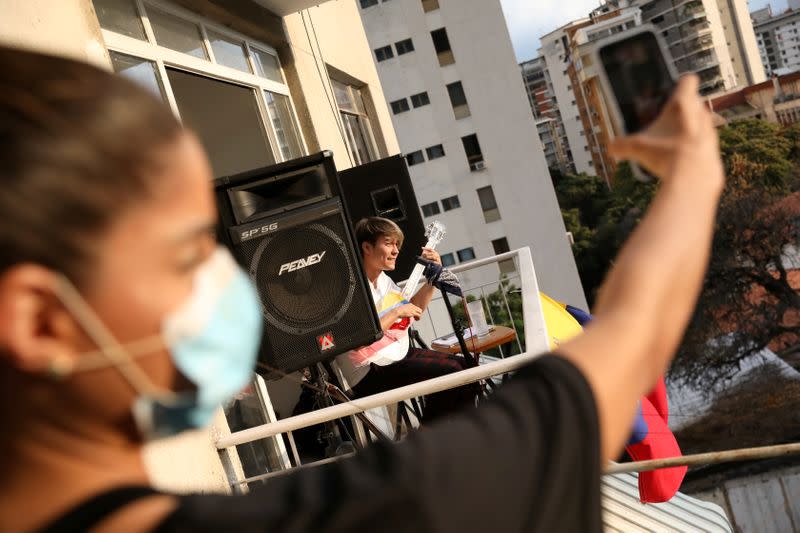 FILE PHOTO: Musician Zandu Montoya sings at the balcony of his house while a friend is recording with a cellphone during the national quarantine in response to the spread of coronavirus disease (COVID-19) in Caracas