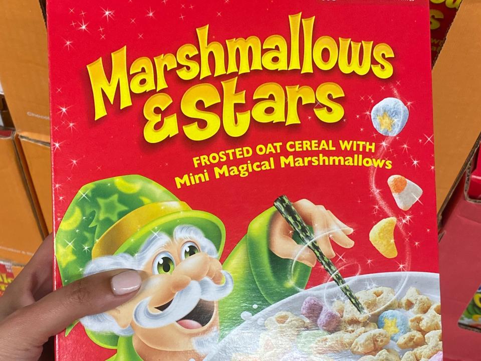 Hand holding red box of marshmallows and stars cereal at Aldi