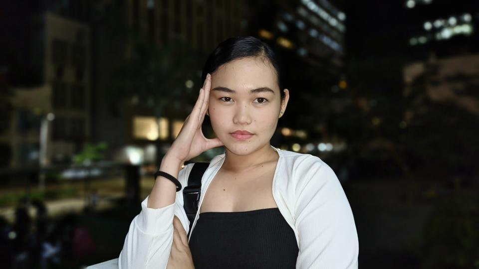 A woman smiling for a photo in front of a bustling cityscape