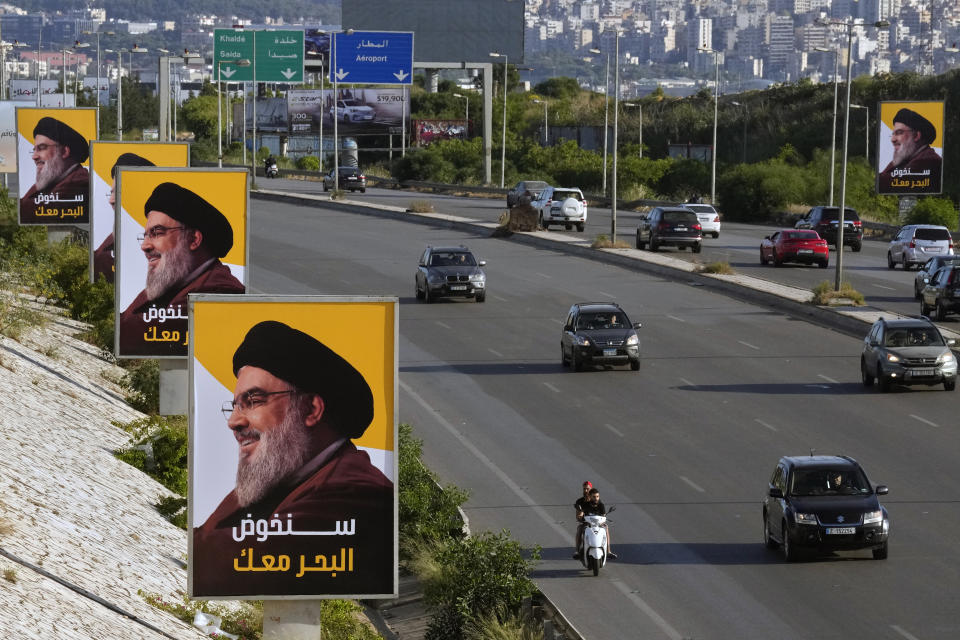 Vehicles drive past posters of Hezbollah leader Sayyed Hassan Nasrallah that were placed as part of Hezbollah elections campaign at the main airport highway, in Beirut, Lebanon, Tuesday, May 10, 2022. Given Lebanon's devastating economic meltdown, Sunday's parliament election is seen as an opportunity to punish the current crop of politicians that have driven the country to the ground. The Arabic text on the posters read"We will ride the high seas with you." (AP Photo/Bilal Hussein)