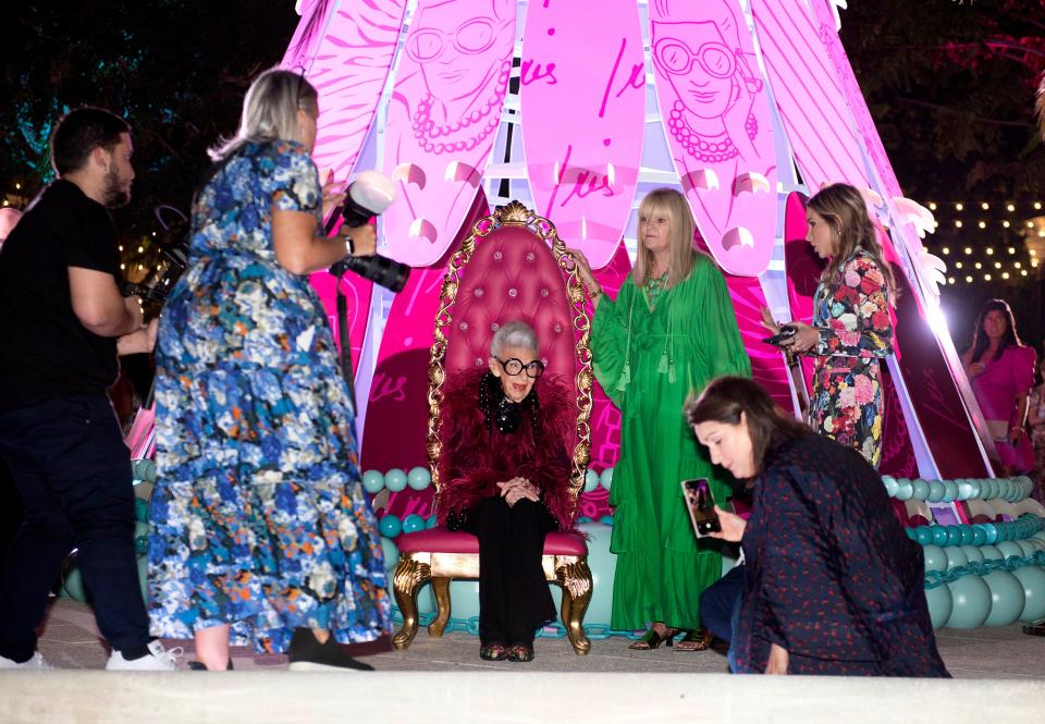 Fashion icon Iris Apfel sits while general manager of The Royal Poinciana Plaza Palm Beach Lori Berg prepares for photos near the holiday surfboard tree designed by Mrs. Apfel during the annual Holiday Tree Reveal and Celebration at the Royal Poinciana Plaza on Dec. 1, 2022.