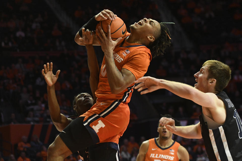 Illinois' Terrence Shannon Jr. (0) is fouled by Monmouth's Myles Ruth, left, as Jack Holmstrom, right, defends during the first half of an NCAA college basketball game, Monday, Nov. 14, 2022, in Champaign, Ill. (AP Photo/Michael Allio)