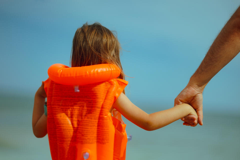 Father protecting her daughter teaching her how to swim