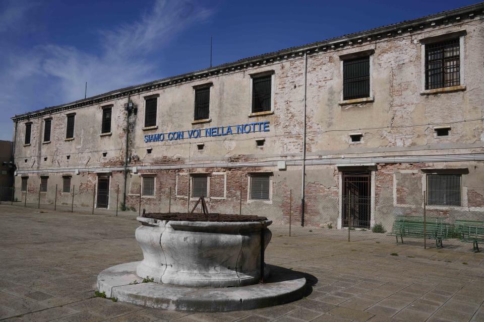 The installation 'Siamo con voi nella notte' (We are with you overnight) by artist Claire Fontaine is displayed inside the women's prison at the Giudecca island during the 60th Biennale of Arts exhibition in Venice, Italy, Wednesday, April 17, 2024. A pair of nude feet dirty, wounded and vulnerable are painted on the façade of the Venice women's prison chapel, the work of Italian artist Maurizio Cattelan and part of the Vatican's pavilion at the Venice Biennale in an innovative collaboration between inmates and artists. (AP Photo/Luca Bruno)