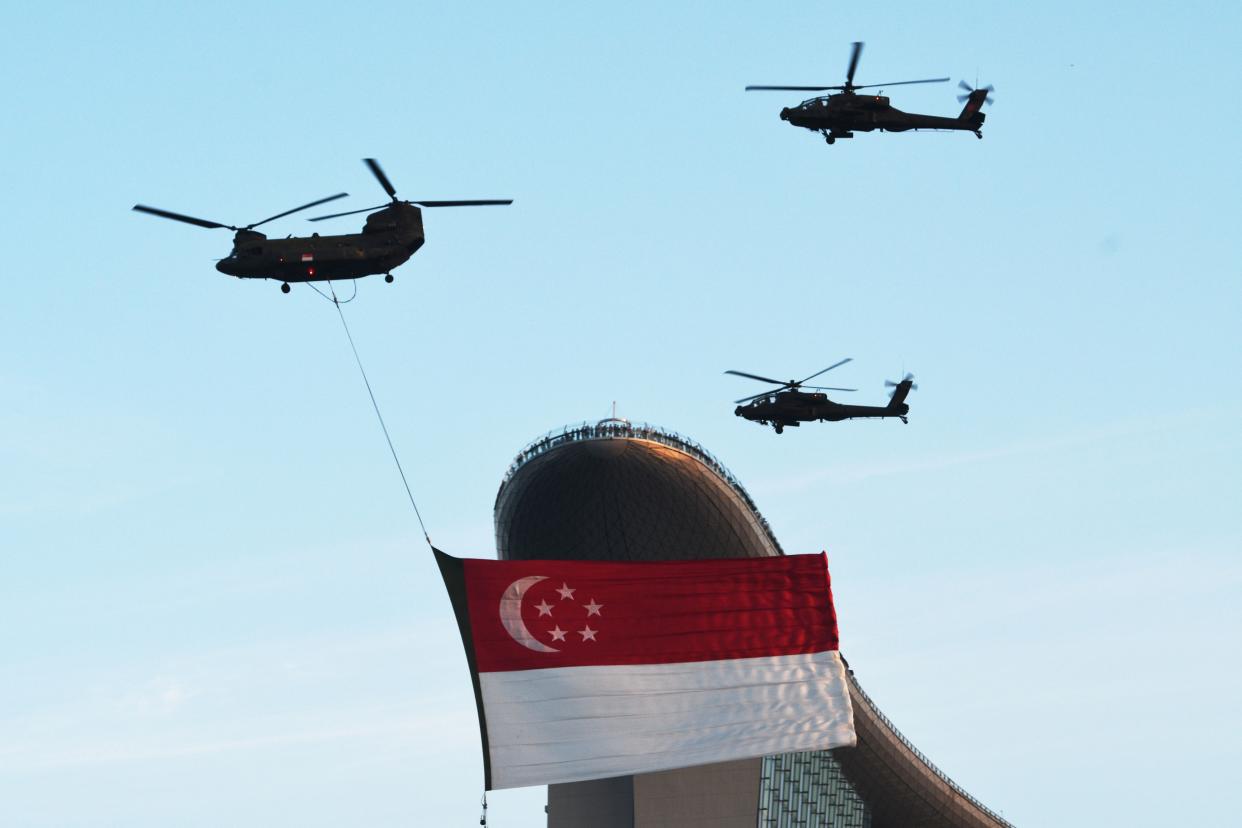 A helicopter towing the Singapore national flag flies in formation during the National Day Parade rehearsal held at Singapore's Marina Bay on 17 July. (PHOTO: Getty Images)