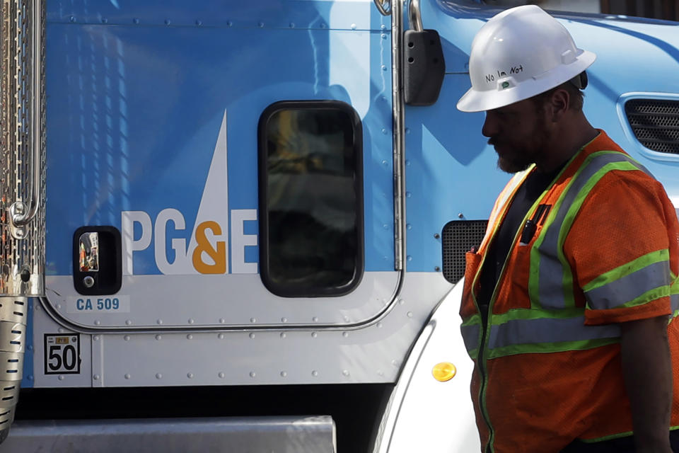 FILE - In this Aug. 15, 2019, file photo, a Pacific Gas & Electric worker walks in front of a truck in San Francisco. PG&E's household customers will be hit with an average rate increase of 8% to help the once-bankrupt utility pay for improvements designed to reduce the risks that its outdated equipment will ignite deadly wildfires in its Northern California service territory. The higher prices, effective March 1, are expected to boost the bills of PG&E's residential customers by an average of $13.44 to per month. (AP Photo/Jeff Chiu, File)