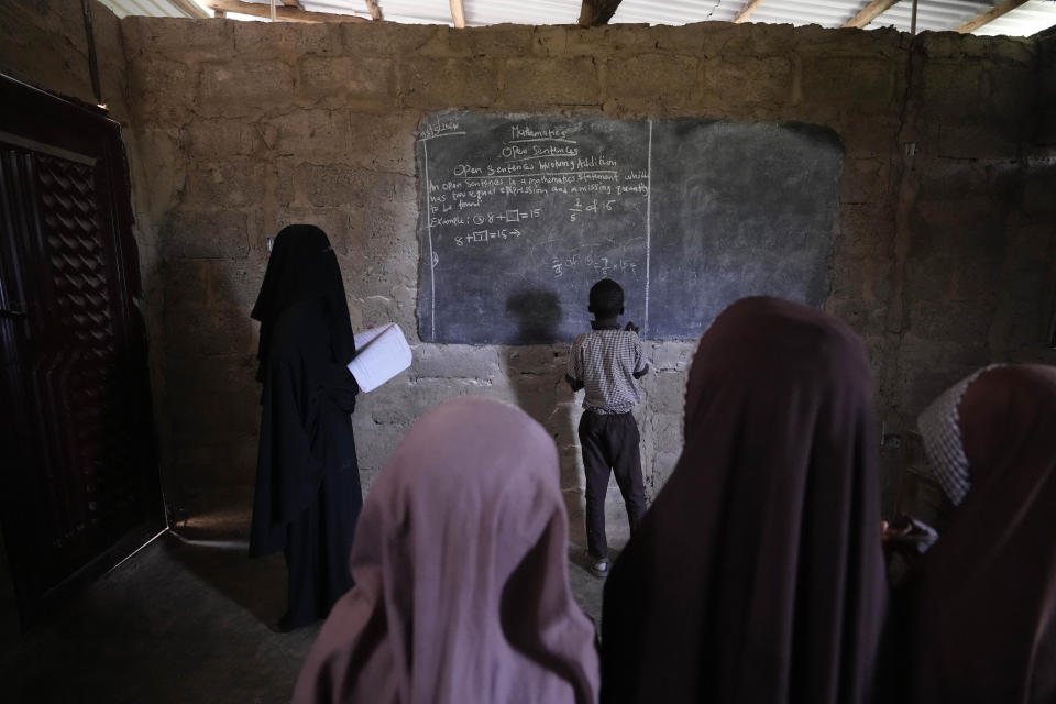 Students of Excellent Moral School attend a lesson in a dimly lit classroom in Ibadan, Nigeria, Tuesday, May 28, 2024. Schools like Excellent Moral operate in darkness due to zero grid access, depriving students of essential tools like computers. (AP Photo/Sunday Alamba)