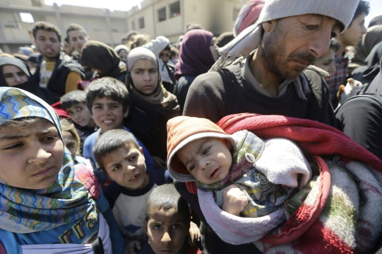 Syrian civilians, evacuated from rebel-held areas in the Eastern Ghouta, gather at a school in the regime-controlled Hosh Nasri, on the northeastern outskirts of the capital Damascus on March 16, 2018, ahead of being relocated to other areas