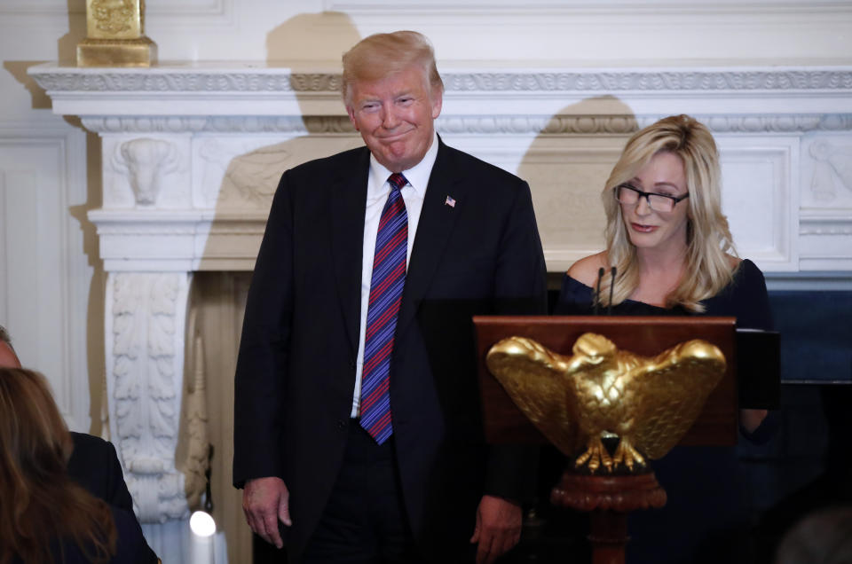 FILE - In this Aug. 27, 2018 file photo, President Donald Trump smiles as pastor Paula White prepares to lead the room in prayer, during a dinner for evangelical leaders in the State Dining Room of the White House. White, now has a formal role in the administration with the Public Liaison office, which oversees outreach to constituent groups seen as key parts of the president’s base. The move giving the Florida-based, tele-evangelist an administration job is seen as another step to solidify his evangelical base as his re-election bid ramps up. (AP Photo/Alex Brandon, File)