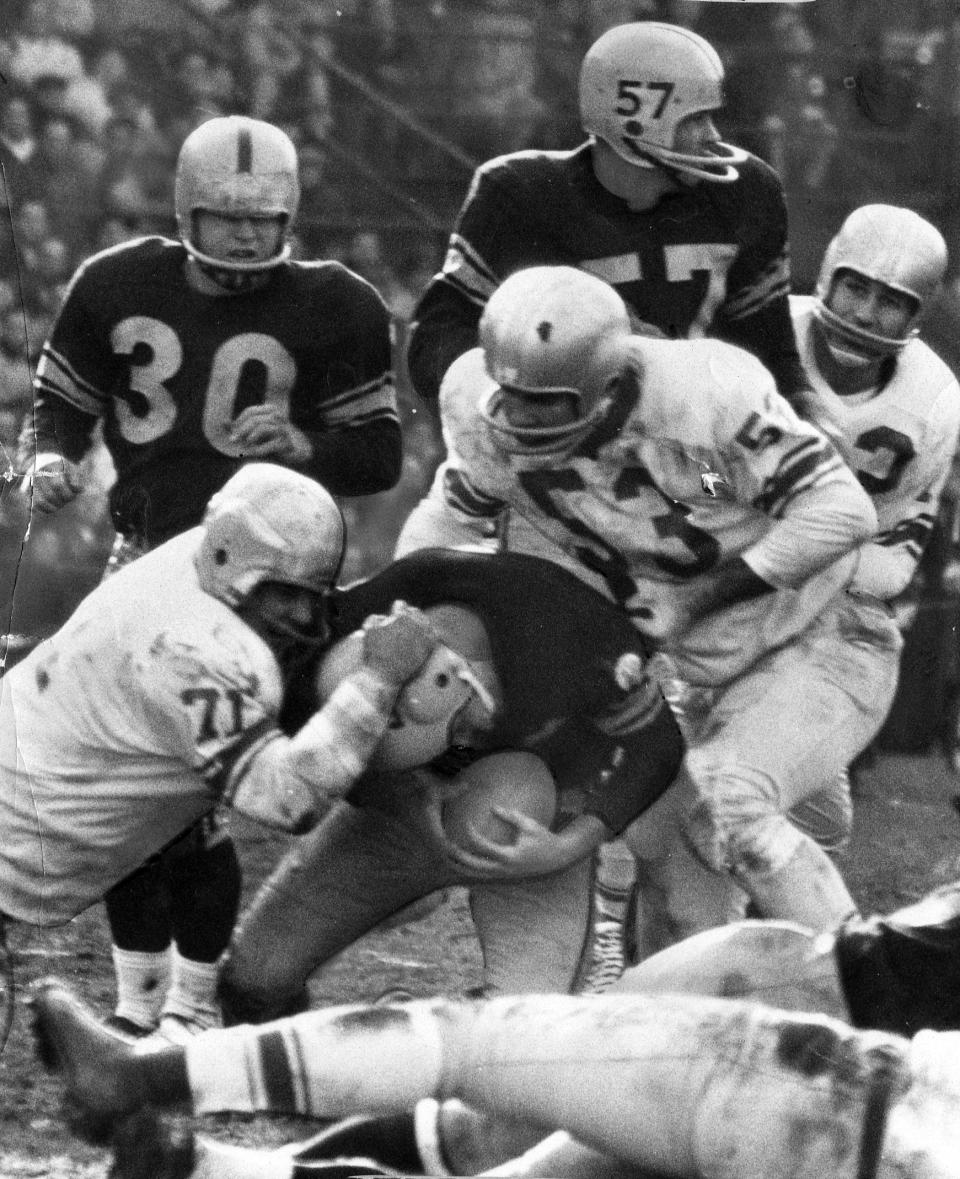 FILE- Detroit Lions defensive tackle Alex Karras (71) helps with the tackle of an unidentified Pittsburgh Steelers football player in Pittsburgh, in this Nov. 8, 1959, file photo. A dozen seasons as one of the most feared pass-rushers in the NFL turned out to be just an opening act for Alex Karras. The Lions' four-time Pro Bowl star was a natural in front of the camera, whether crumpling quarterbacks, needling then-commissioner Pete Rozelle or sharing stories with Johnny Carson on “The Tonight Show.” Karras used that tough-guy image to launch a second career as a sportscaster, and a sitcom and movie star. (The Detroit News via AP)