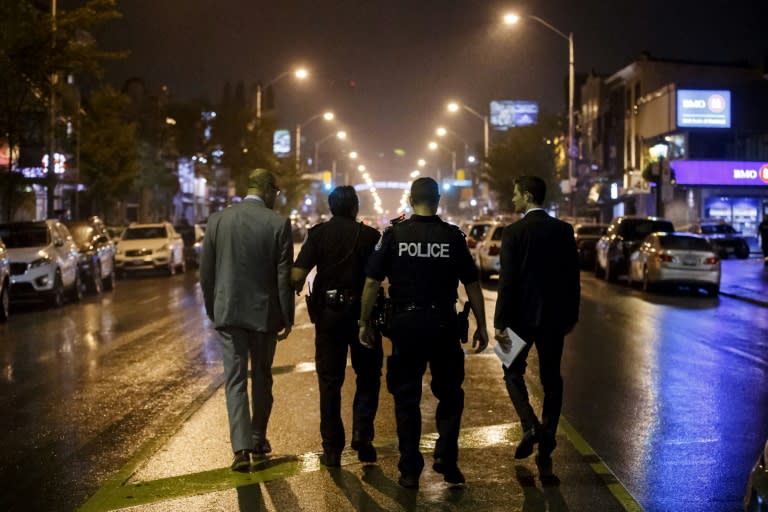 Toronto Police officers work on Danforth Avenue, at the scene of a shooting that left two people dead and 13 wounded