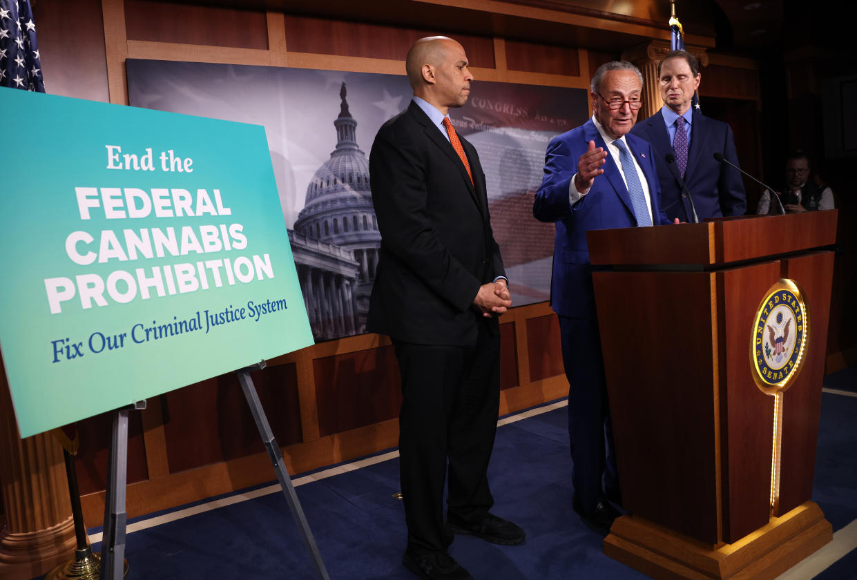 Sen. Chuck Schumer speaks at a podium with two other senators near a sign that reads: End the Federal cannabis Prohibition