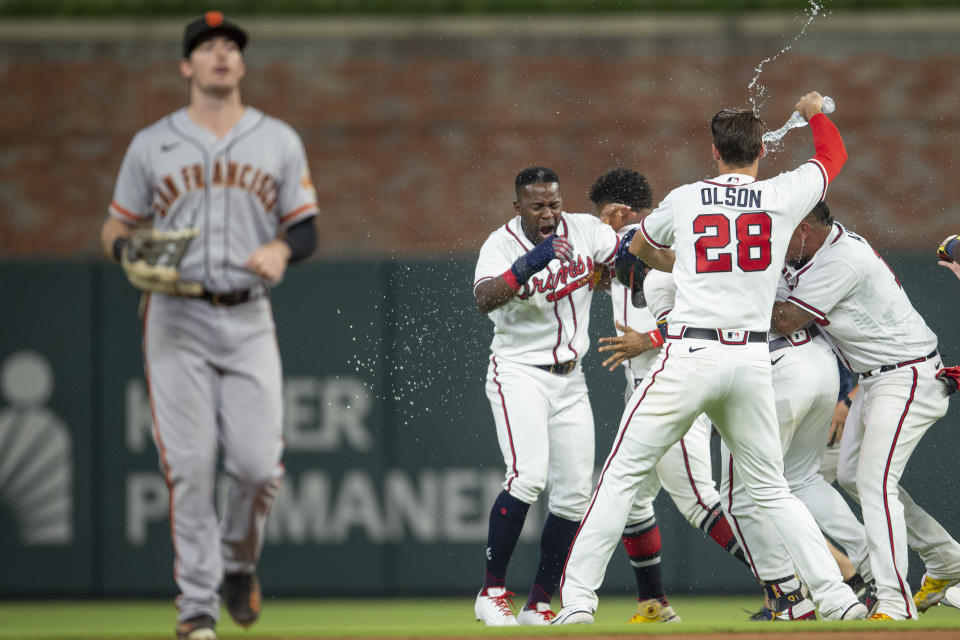 San Francisco Giants right fielder Mike Yastrzemski leaves field as Atlanta Braves Matt Olson (28) throws water on teammates in celebration during the ninth inning of a baseball game Wednesday, June 22, 2022, in Atlanta. (AP Photo/Hakim Wright Sr.)