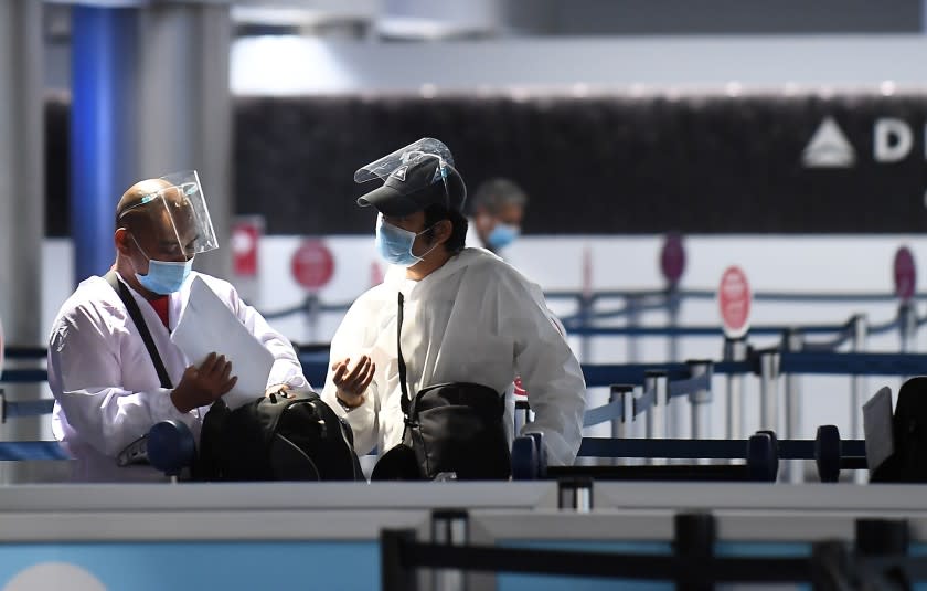 Travelers wearing full body suit sand masks prepare to head to there gate at Terminal 2 at LAX Friday.