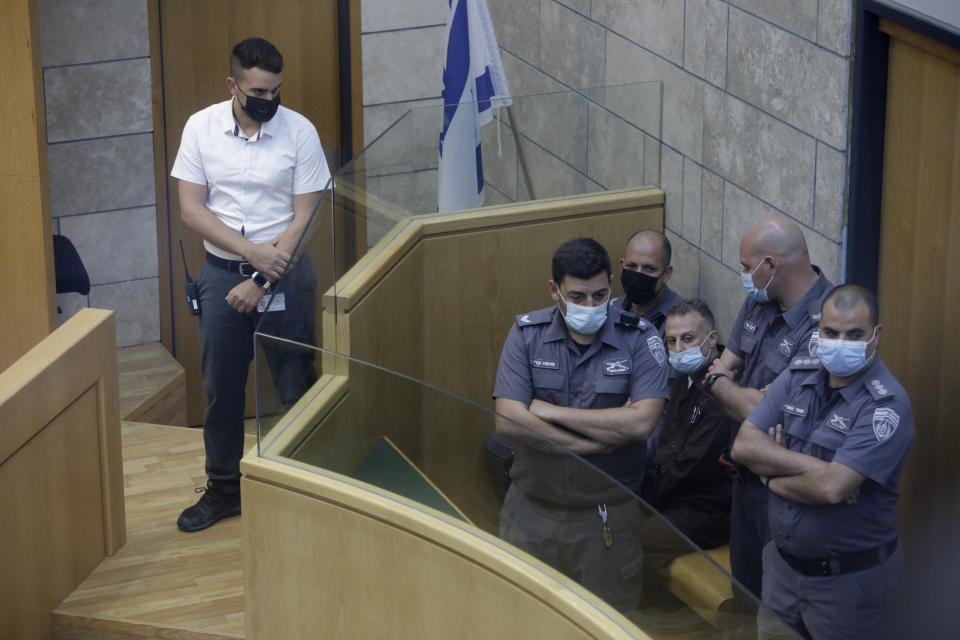 Yakub Kadari is surrounded by guards in a courtroom in Nazareth, Israel, after he and three other Palestinian fugitives were captured on Saturday, Sept. 11, 2021. Israeli police on Saturday said they have arrested four of the six Palestinians who broke out of a maximum-security prison this week — including a famed militant leader whose exploits over the years have made him a well-known figure in Israel. (AP Photo/Sebastian Scheiner)