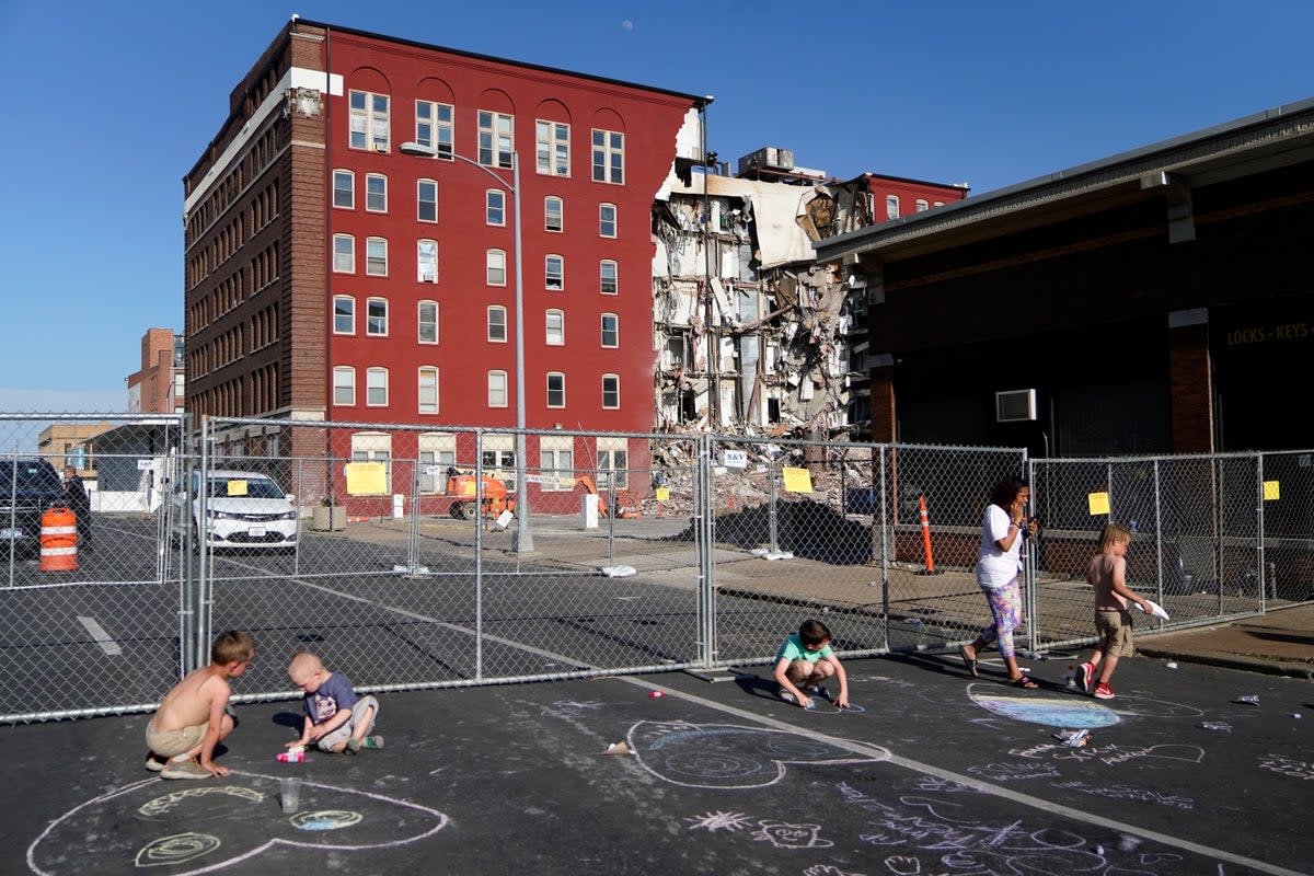 Children draw on the ground with chalk at the scene where an apartment building partially collapsed on Sunday afternoon (Copyright 2023 The Associated Press. All rights reserved.)