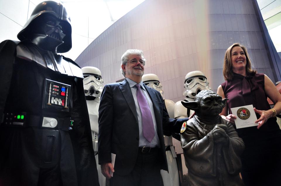 Filmmaking legend George Lucas (L)and Kathleen Kennedy (R) president of Disney's Lucasfilms pose with Stormtroopers (back) and Darth Vader (L) characters from Lucas' Star Wars films at the opening of Disney's Lucasfilms' new animation production facility, the Sandcrawler in Singapore on January 16, 2014. AFP PHOTO / STEFANUS IAN        (Photo credit should read STEFANUS IAN/AFP via Getty Images)