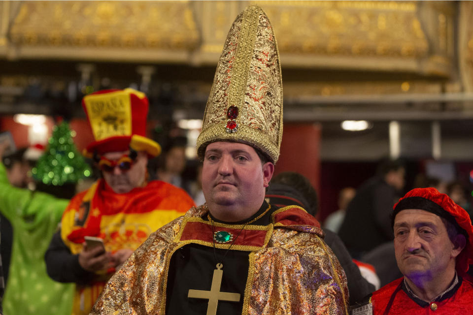 People in the costumes wait for the start of the Christmas lottery draw at Madrid's Teatro Real opera house during Spain's bumper Christmas lottery draw in Madrid, Spain, Sunday, Dec. 22, 2019. The lottery, known as El Gordo, or The Fat One, will dish out 2.24 billion euros ($2.43 billion) in prizes. (AP Photo/Paul White)