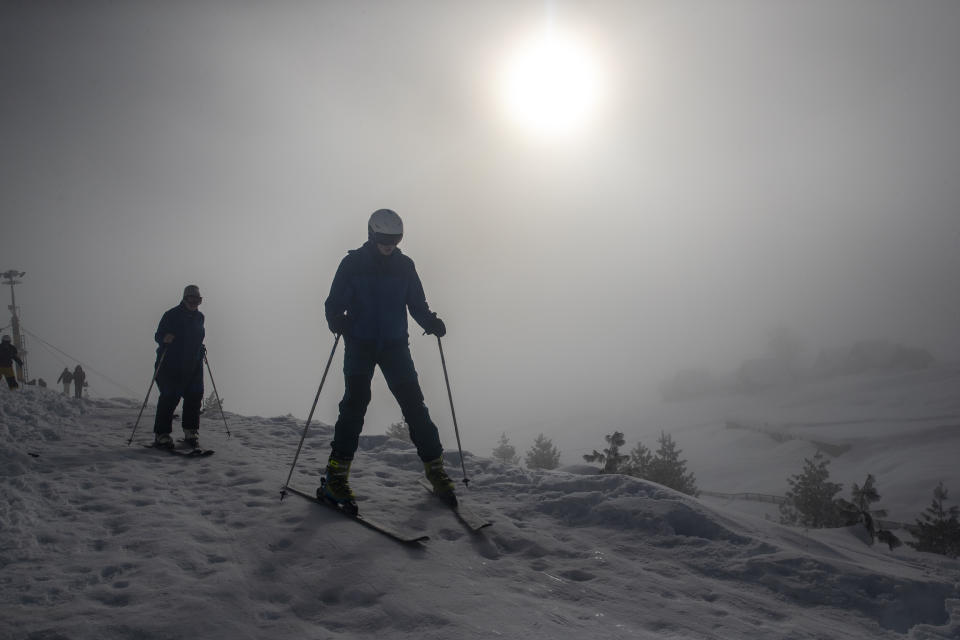 Tourists from Holland ski down a slope as fog engulfs the background in Gulmarg, northwest of Srinagar, Indian controlled Kashmir, Monday, Jan. 11, 2021. Snow this winter has brought along with it thousands of locals and tourists to Indian-controlled Kashmir's high plateau, pastoral Gulmarg, which translates as “meadow of flowers." (AP Photo/ Dar Yasin)