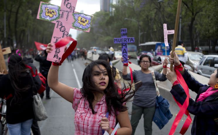 A woman carries a cross that reads in Spanish 