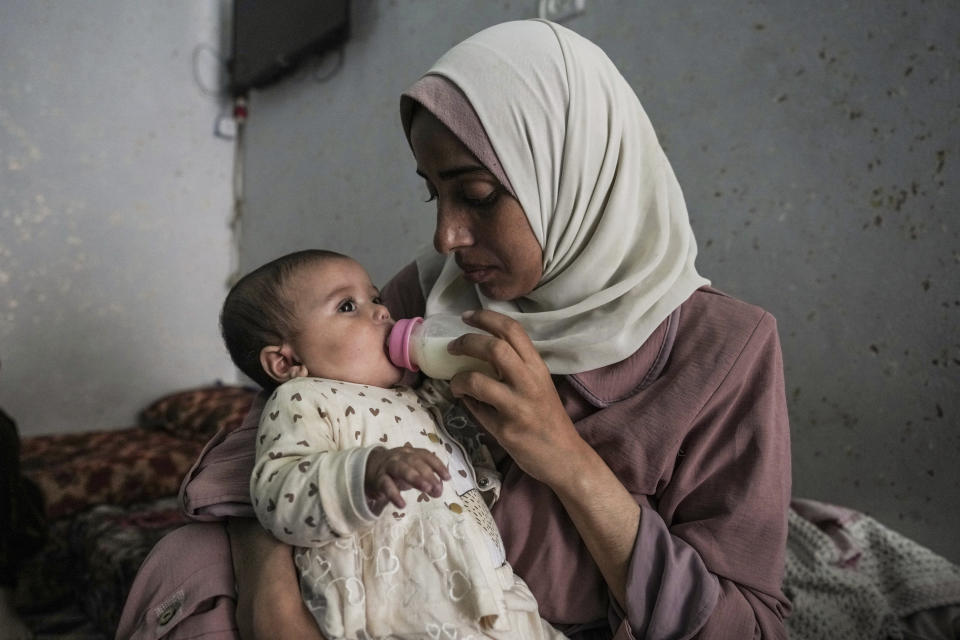 CORRECTS LOCATION - Rola Saqer feeds her baby Masa Mohammad Zaqout at her parents' home in the neighborhood of Zawaida, central Gaza, Thursday, April 4, 2024. Zaqout was born Oct. 7, the day the Israel- Hamas war erupted. Mothers who gave birth that day fret that their 6-month-old babies have known nothing but brutal war, characterized by a lack of baby food, unsanitary shelter conditions and the crashing of airstrikes. (AP Photo/Abdel Kareem Hana)