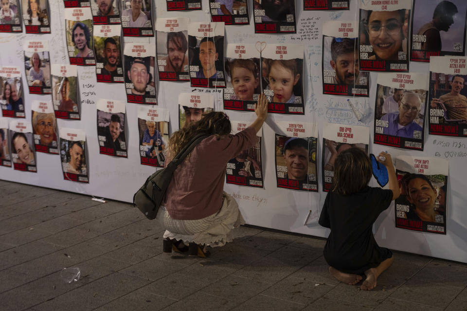 FILE - A woman touches photos of Israelis missing and held captive in Gaza, displayed on a wall in Tel Aviv on Oct. 21, 2023. One of the missing, Ohad Munder-Zichri, turned 9 on Monday. But instead of celebrating at home with his family and friends, he was somewhere in Gaza, one of more than 200 Israelis held hostage by Hamas since their devastating Oct. 7 incursion. (AP Photo/Petros Giannakouris, File)