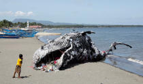 <p>A boy looks at a whale shaped art installation that is made of plastic and trash made by environmental activist group Greenpeace Philippines, lying along the shore in Naic, Cavite, in the Philippines May 12, 2017. (Photo: Erik De Castro/Reuters) </p>