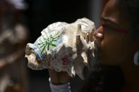 A woman blows on a conch shell as she takes part in a march demanding statues and street names commemorating symbols of colonial oppression be removed, in San Juan, Puerto Rico, Saturday, July 11, 2020. Dozens of activists marched through the historic part of Puerto Rico’s capital on Saturday to demand that the U.S. territory’s government start by removing statues, including those of explorer Christopher Columbus. (AP Photo/Carlos Giusti)