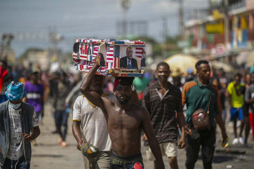 Demonstrators carry a mock coffin with the image of Prime Minister Ariel Henry during a protest to reject an international military force requested by the government and to demand the resignation of Henry, in Port-au-Prince, Haiti, Monday, Oct. 17, 2022. The United Nations Security Council is evaluating the request by the Haitian government for the immediate deployment of foreign troops to help free Haiti from the grip of gangs that has caused a scarcity of fuel, water and other basic supplies. (AP Photo/Odelyn Joseph)