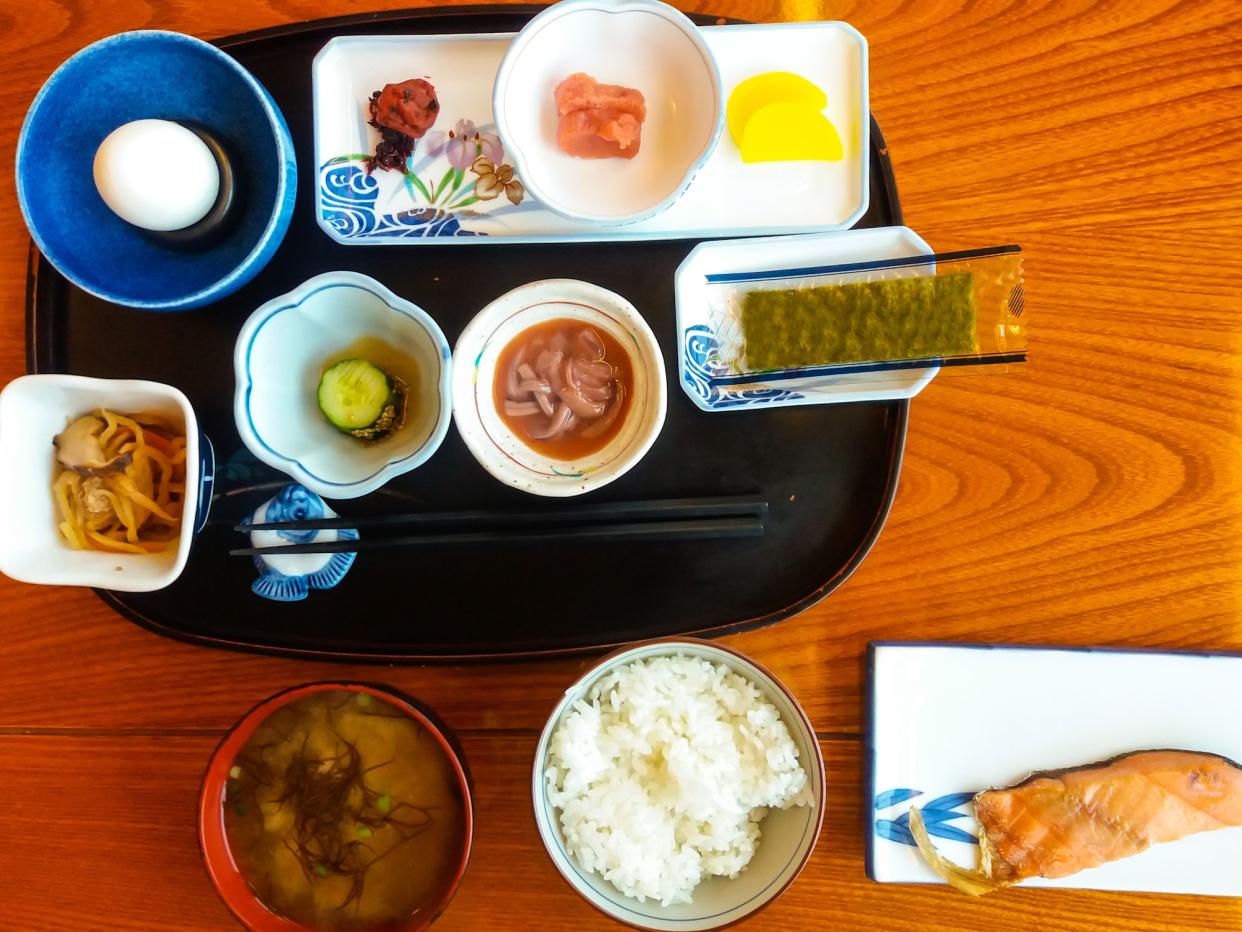Serving sice of grilled salmon, rice, squid, miso soup, egg and pickel. Hokkaido, Japan.