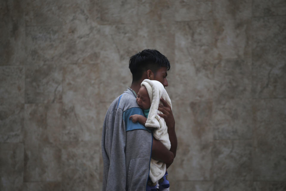 A Central American migrant making their way to the U.S. in a large caravan carries his son after arriving in Tapachula, Mexico, Sunday, Oct. 21, 2018. The man said a truck driver gave them a free ride to the city. A growing caravan of Honduran migrants streamed through southern Mexico on Sunday heading toward the United States, after making an end-run around Mexican agents who briefly blocked them at the Guatemalan border. (AP Photo/Moises Castillo)