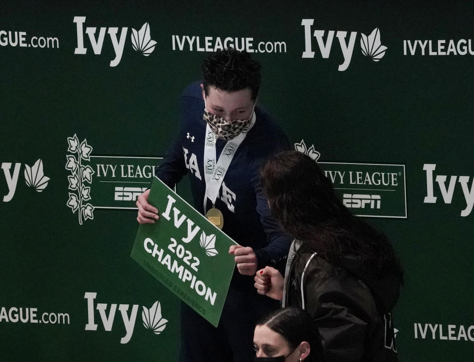 Yale's Iszac Henig is congratulated on the podium after winning the 50-yard freestyle at the Ivy League women's swimming and diving championships at Harvard University, Thursday, Feb. 17, 2022, in Cambridge, Mass. Henig, who is transitioning to male but hasn't begun hormone treatments yet, is swimming for the Yale women's team. (AP Photo/Mary Schwalm)