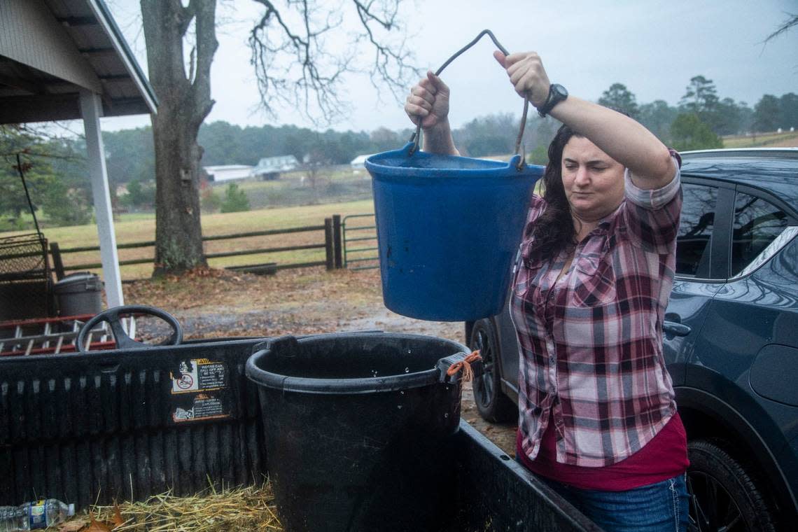 Without power to run a well pump, Sarah Baker carries water to a horse barn Wednesday morning, Dec. 7, 2022 at Fox Lake Farm in Southern Pines. Two deliberate attacks on electrical substations in Moore County Saturday evening caused days-long power outages for tens of thousands of customers.