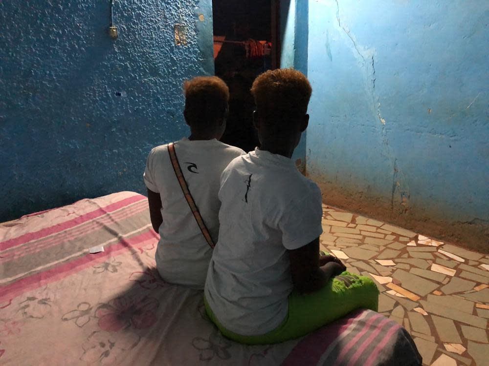 Two Nigerian sex workers sit on a bed in a room, at a bar in Burkina Faso’s town of Bobo-Dioulasso 360 kms (220 miles) West of Ouagadougou, June 6, 2020. Both women said they were trafficked from Nigeria and forced into prostitution. Now free from their captors, they’re too ashamed to return home without money so they continue sex work. As part of a months-long investigation into sex trafficking and the gold mining industry, The Associated Press met with nearly 20 Nigerian women who said they had been brought to Burkina Faso under false pretenses, then forced into prostitution. (AP Photo/Sam Mednick)