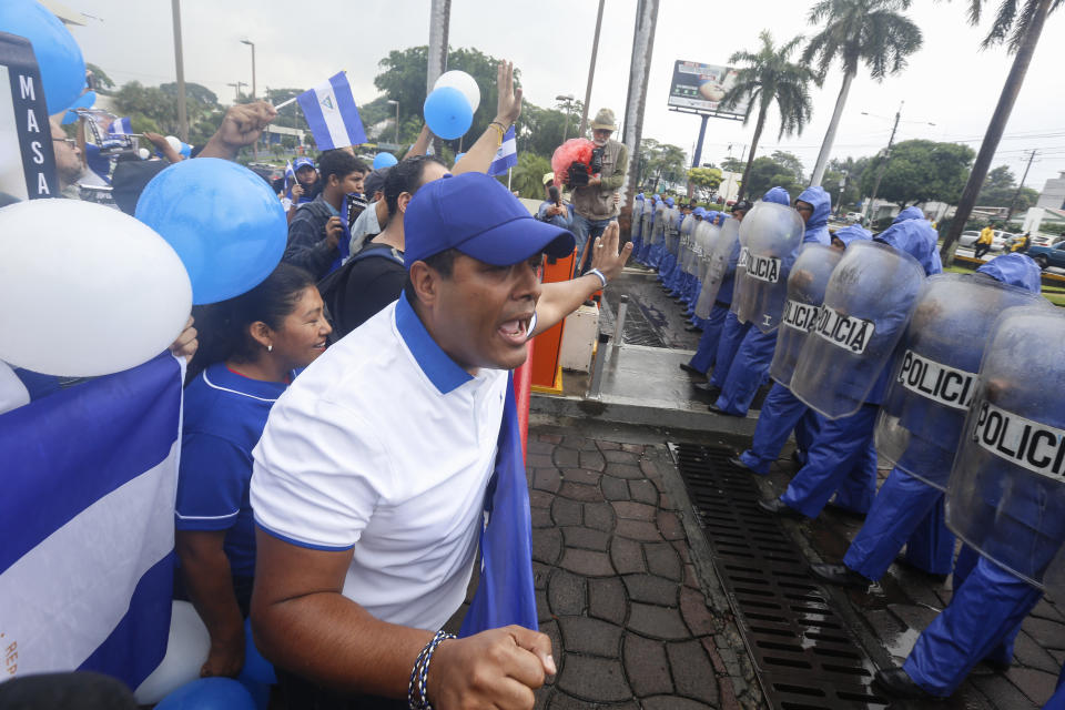 Demonstrators confront a cordon of police during an anti-government march dubbed, "Nothing is Normal” in honor of Matt Romero, in Managua, Nicaragua, Saturday, Sept. 21, 2019. 16-year-old Matt Romero was killed during “crossfire” last September when armed men wearing hoods clashed with anti-government protesters. (AP Photo/Alfredo Zuniga)