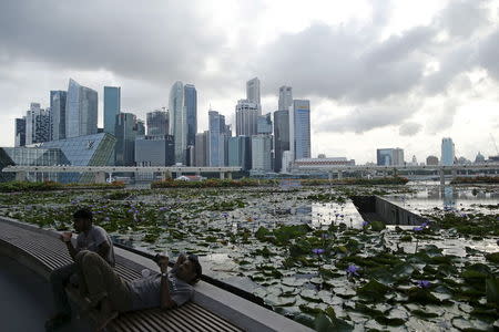 Labourers take a break at the end of the work day against the backdrop of the financial district of Singapore in this August 6, 2014 file photo. REUTERS/Edgar Su/Files