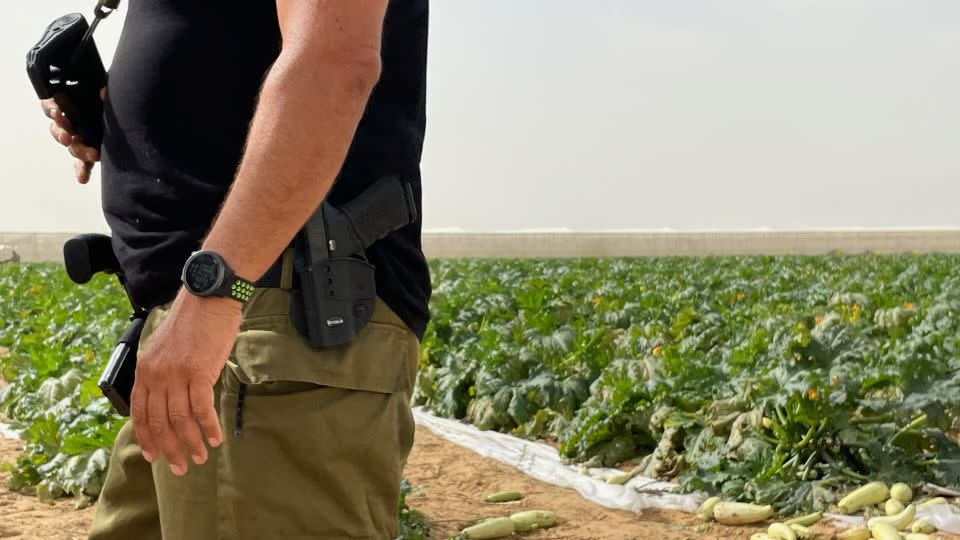 Since the October 7 attacks, farmer Yosi Inbar patrols his fields with his rifle to protect his staff and volunteers. - Joseph Ataman/CNN