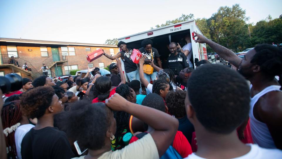 Real Boston Richey hands out shoes to children and families at Holton Apartments in Tallahassee, Fla. on Monday, Aug. 15, 2022.