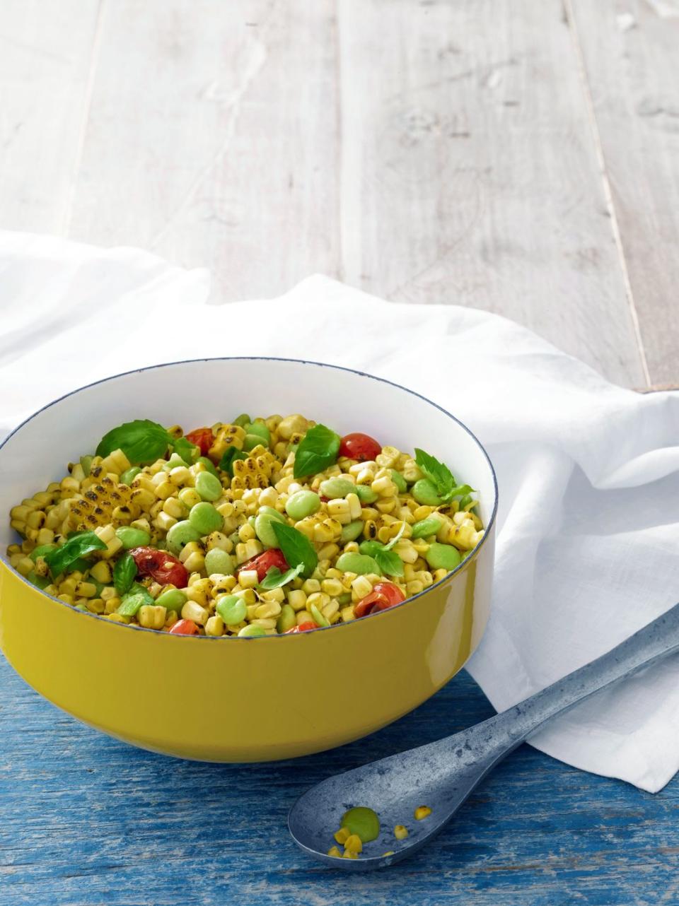 grilled succotash in a yellow enamel serving bowl with a vintage metal serving spoon