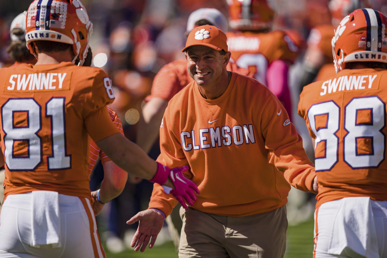 Clemson head coach Dabo Swinney smiles as he hi fives wide receiver Drew Swinney (81) and wide receiver Clay Swinney (88) before an NCAA college football game against Syracuse on Saturday, Oct. 22, 2022, in Clemson, S.C. (AP Photo/Jacob Kupferman)